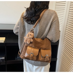Detail of a brown vintage tote bag featuring suede texture and two front buckled pockets