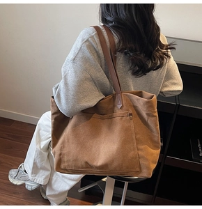 Detail of a large brown canvas tote bag with retro leather straps for daily commute