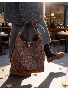Detail of leopard print bucket bag with metal buckle in a natural outdoor cafe setting
