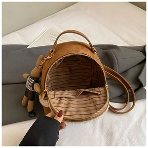 Detail view of brown suede backpack interior with striped lining and plush bear charm