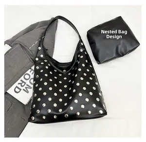 Detail view of black rivet shoulder bag set with small pouch on a stylish fabric background