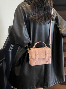Sac à main plissé rose avec détails dorés porté par un mannequin dans un décor moderne