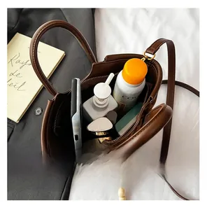 Top view of spacious brown leather bucket bag interior showing smartphone and cosmetics