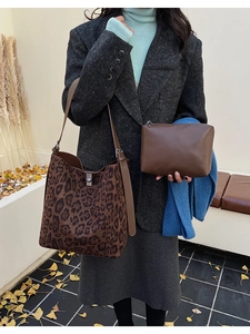 Detailed set of leopard print bucket bag and brown clutch with autumn leaves background