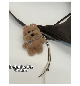 Macro shot of brown plush dog pendant with pearl necklace and bone charm on leather bag