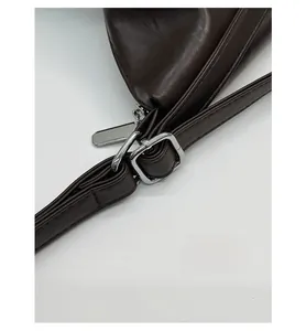 Detail of dark brown leather strap with polished silver adjustable buckle and zipper