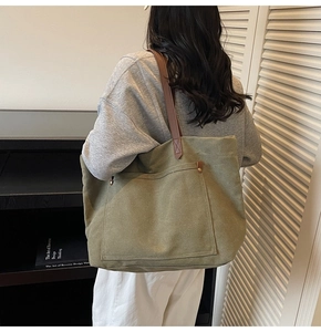 Close-up of olive green canvas tote bag with brown leather straps shown on a model