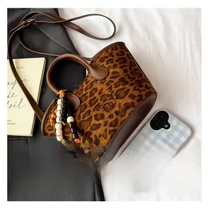 Close-up of leopard print bucket bag featuring brown leather strap and wood bead charm