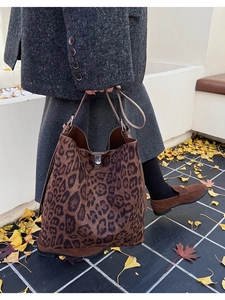 Chic leopard print bucket bag with metal lock shown in an autumn street setting