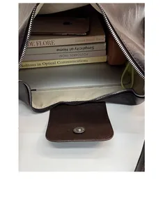 Top view of spacious dark brown tote bag interior filled with books and a laptop