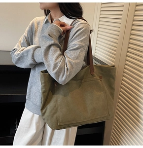Detail view of vintage olive canvas tote bag with brown leather straps and metal rivets