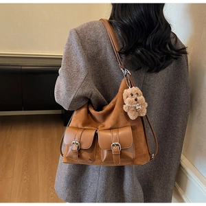 Detail of vintage brown suede tote bag featuring front buckle pockets and plush bear charm
