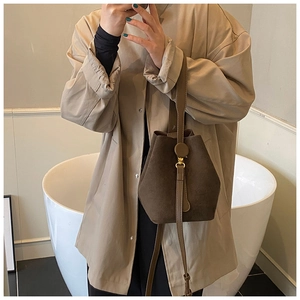 Detail of a vintage matte dark brown suede bucket bag with slim leather shoulder strap