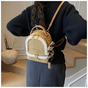 Detail of khaki suede backpack with faux fur trim and cute rabbit doll keychain