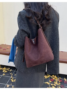 Close-up of brown frosted suede tote bag with metal square buckle on outdoor bench