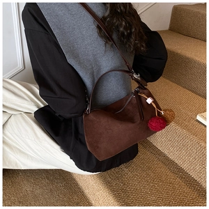 Détail d'un sac à main en daim givré avec pompons décoratifs et breloques en perles