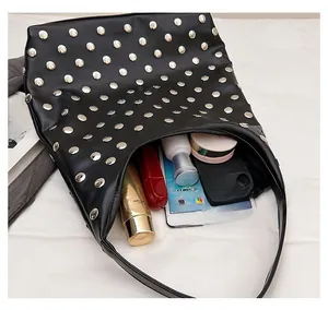 Detail of black leather hobo bag with silver studs showing spacious interior for essentials