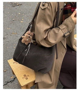 Gros plan du grand sac hobo en daim anthracite avec un charmant pendentif chiot en peluche