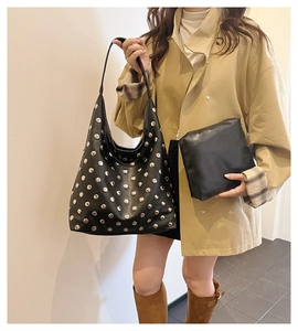 Detail of black studded hobo bag and matching zip pouch set shown with model