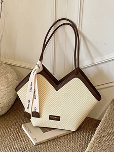 Minimalist V-shaped woven tote bag with brown leather trim and decorative silk scarf