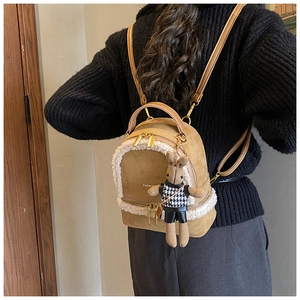 Close-up of camel suede mini backpack with faux fur trim and cute rabbit doll charm