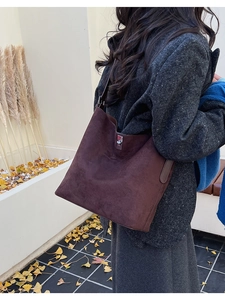 Detailed view of dark brown suede bucket bag with silver rotating clasp in an outdoor setting