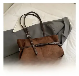 Détail macro du daim marron avec boucle argentée et bandoulière en cuir sur le cabas