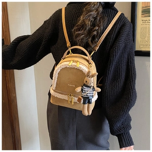 Detail of mini backpack with brown matte fabric, plush trim, and rabbit charm