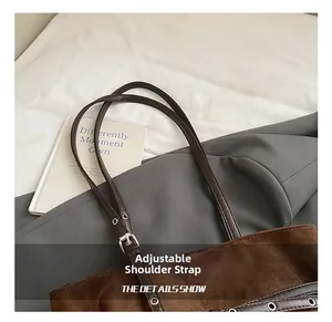 Détail de la bandoulière réglable en cuir et boucle argentée sur le sac cabas en daim marron