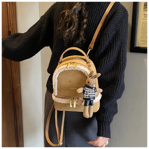 Close-up of khaki mini backpack with white faux fur trim and cute bunny plush pendant