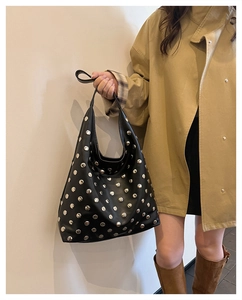 Close-up of black hobo bag with silver metal studs shown on a shoulder