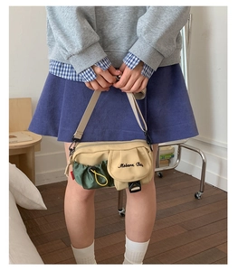 Detail of vintage canvas crossbody bag showing olive green drawstring pocket and buckle closure