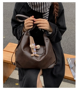 Detail of dark brown vintage PU leather tote bag with a cute long-eared dog charm