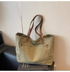 Detail of army green canvas tote with brown leather straps and vintage bronze rivets