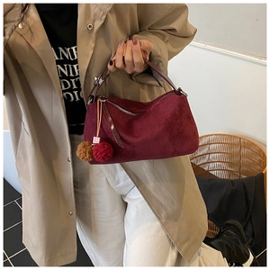 Détails de texture du sac à main bordeaux en daim avec deux pompons décoratifs