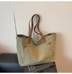 Close-up of olive green canvas tote bag with brown leather straps and metal rivets