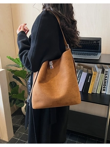 Detail of a brown suede hobo bag with a silver twist lock closure on a shoulder strap
