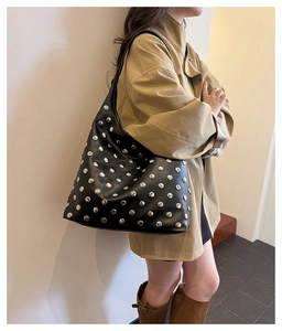 Detail of black leather tote bag with silver metal studs and large capacity structure