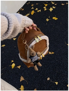 Detailed side view of brown suede mini backpack with shearling trim and rabbit charm