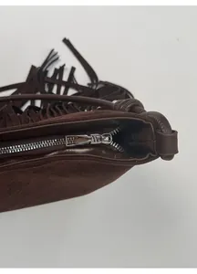 Detail von Silberreißverschluss und böhmischen Fransen an dunkelbrauner Wildledertasche