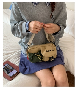 Detail view of khaki and green workwear crossbody bag with pocket and buckle details