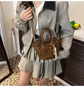 Leopard print bucket bag with suede texture and wooden bead charm shown on model