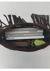 Draufsicht auf den geräumigen Innenraum der braunen Wildledertasche mit Fransen und Büchern