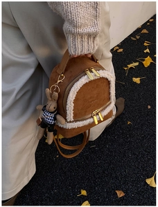 Detail of mini brown suede backpack with faux shearling trim and bunny keychain charm