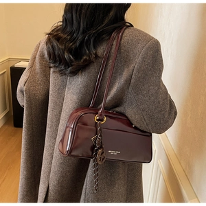 Détail du sac oreiller en cuir verni bordeaux avec pompon et longue bandoulière