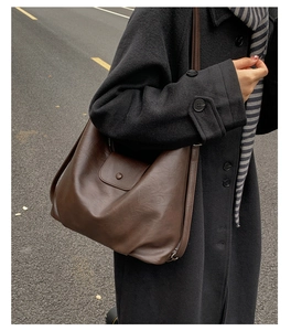 Macro view of a soft brown leather tote bag showing fine texture and magnetic buckle flap