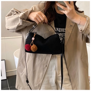 Detail of black suede hobo bag featuring a cute cherry charm and adjustable strap