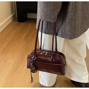 Sac oreiller vintage rouge foncé porté par un mannequin pour un look chic et urbain