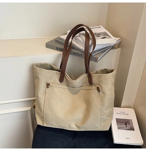 Macro shot of minimalist canvas tote with premium brown leather handles and stitched pockets