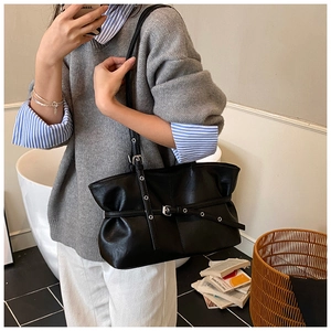 Détail du sac cabas en cuir noir avec sangle décorative à œillets argentés et boucle en métal